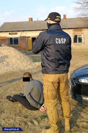 Policjant CBŚP z zatrzymanymi osobami.