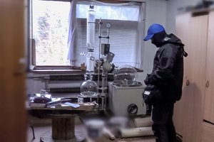 policjant CBŚP stoi w pomieszczeniu z urządzeniami do produkcji narkotyków