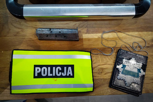 Magazynek od pistoletu, opaska z napisem &quot;POLICJA&quot;, oraz odznaka policyjna leżące na blacie stołu.
