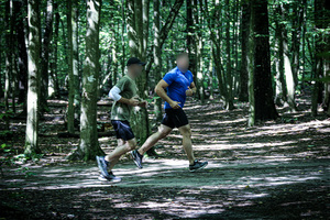 Dwóch policjantów w strojach do ćwiczeń biegnących w lesie.