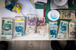 Pliki banknotów o nominałach 20, 50, 100 i 200 PLN leżące na blacie stołu.